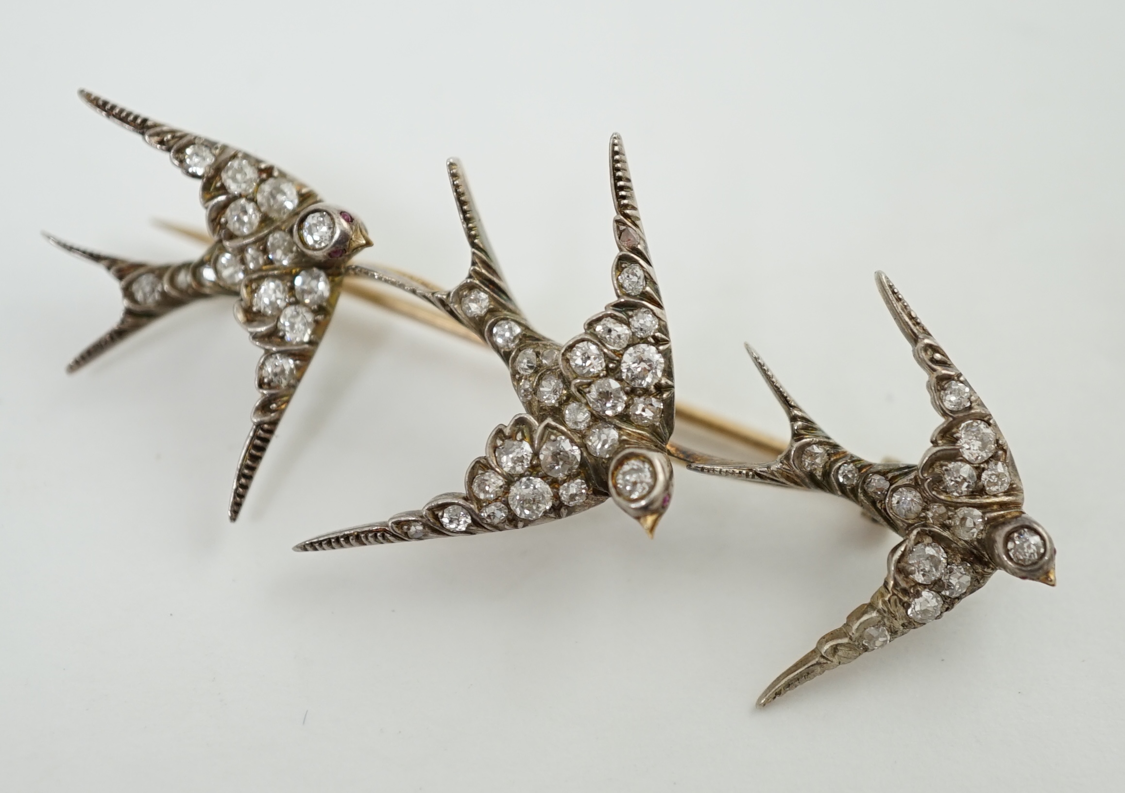 An Edwardian gold and graduated diamond cluster set triple swallow bar brooch